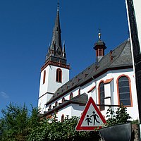 Die Kirche in Erbach mit weißer Fassade, roten Details und schwarz-grauem Schieferdach in der Grundform einer Basilika mit hohem Glockenturm